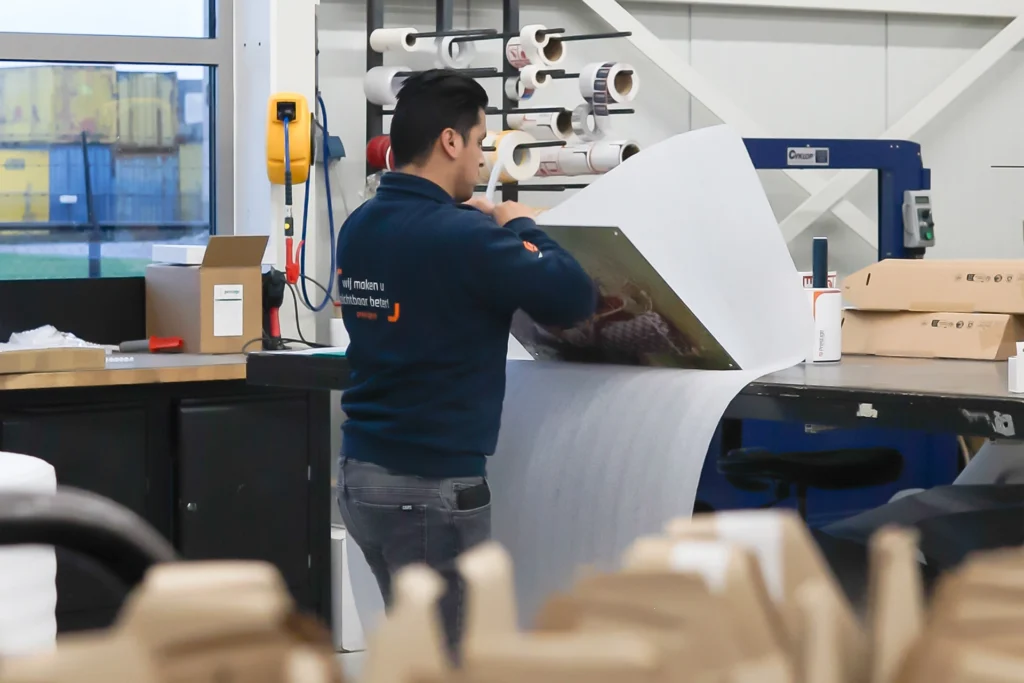 Een medewerker van Prestige Reclame pakt een fotopaneel in voor verzending.