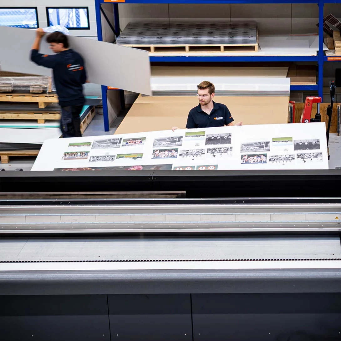 Medewerker in de productiehal haalt een grote print van de printer.